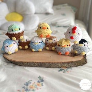 May include: A collection of nine crocheted animal figurines, including a penguin, a chick, a rooster, and a variety of birds. The figurines are arranged on a wooden surface and are all facing the camera.