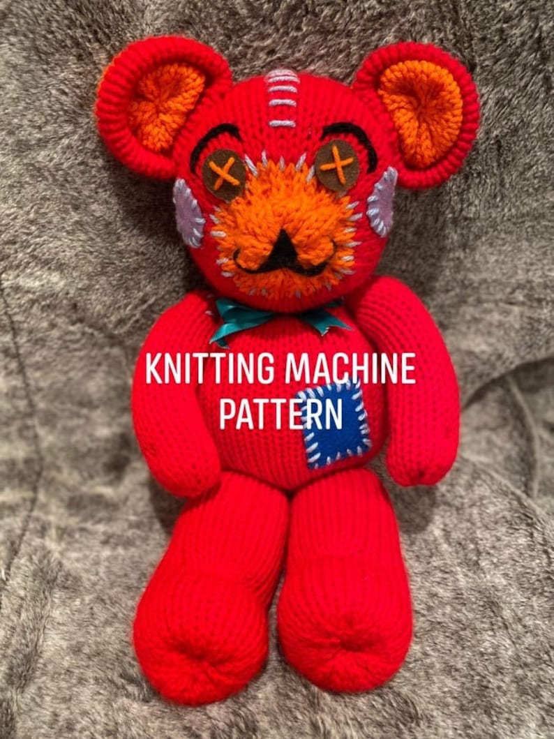 May include: Red knitted teddy bear with a stitched-on face, including a mustache and X's for eyes. The bear has a blue and white patch on its leg and the text "KNITTING MACHINE PATTERN" is printed on its chest.