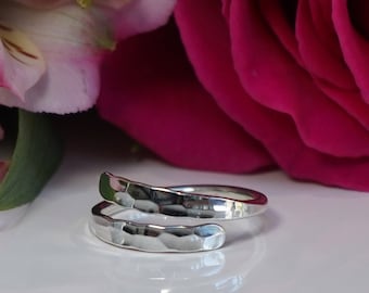 May include: A silver hammered wrap ring with a smooth, polished finish. The ring is open and adjustable to fit most finger sizes.