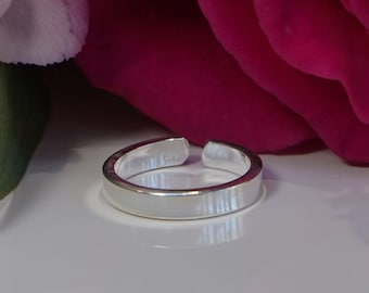 May include: A silver toe ring with a smooth, polished finish. The ring is open at the back and is designed to be adjustable.