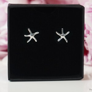 May include: A pair of silver starfish earrings in a black velvet box. The earrings are small and delicate, and they would make a great gift for someone who loves the ocean.