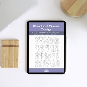 May include: A digital tablet displaying a purple and white ebook cover titled "Practical Dress Design: A 1950s Pattern-Making Guide with Hundreds of Designs". The cover features a collection of vintage dress designs.