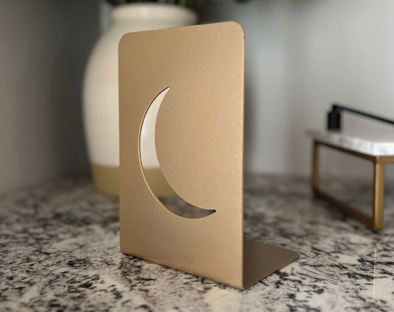 May include: Gold metal bookends with a crescent moon cut-out design.
