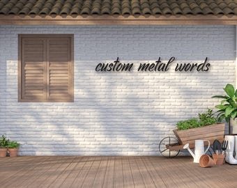 May include: A white brick wall with a window and a sign that reads "custom metal words". There is a wooden deck in the foreground with a wheelbarrow, gardening tools, and potted plants.