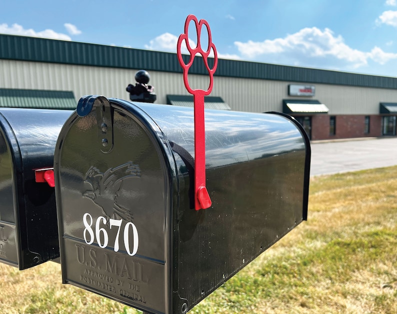 Może przedstawiać: Czarna skrzynka pocztowa z czerwoną flagą w kształcie łapy. Skrzynka pocztowa ma numer 8670 i tekst "U.S. MAIL APPROVED BY THE POSTMASTER GENERAL".