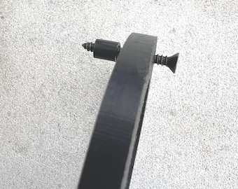 May include: A close-up of a black metal ring with two screws. The ring is attached to a wall or other surface.