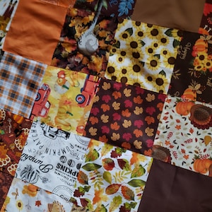 May include: A patchwork quilt with a variety of fall-themed fabrics. The fabrics feature pumpkins, sunflowers, leaves, and turkeys. The quilt is made up of squares of different sizes and colors. The quilt is a great way to add a touch of fall to your home.