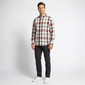 Puede incluir: Una persona con una camisa a cuadros crema, roja, azul marino y verde. Se combina con pantalones grises oscuros y zapatillas blancas. El conjunto es informal y adecuado para el uso diario.