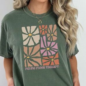 May include: A green t-shirt with a graphic of colorful flowers and the text "Pelvic Floor Therapy!"