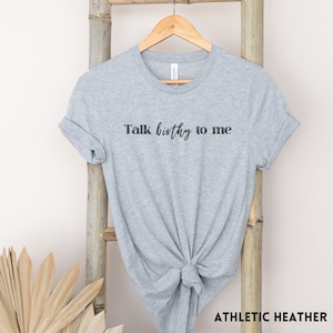 Puede incluir: Una camiseta gris jaspeada con el texto "Talk birthy to me" impreso en negro.