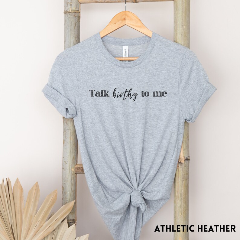 Puede incluir: Una camiseta gris jaspeada con el texto "Talk birthy to me" impreso en negro.