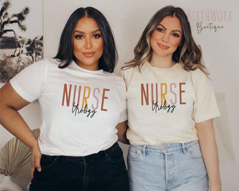 May include: Two people wearing white and cream short-sleeved t-shirts with the text "NURSE Urology" in colorful letters. The text is in a layered, stacked font style.