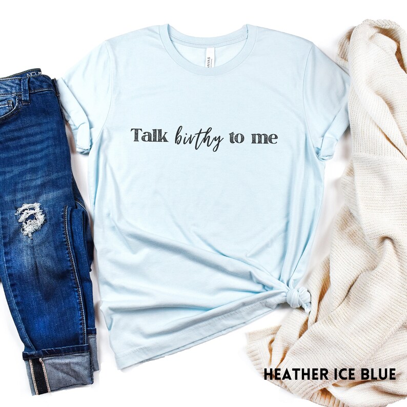 Puede incluir: Una camiseta azul claro con el texto "Talk birthy to me" en letras negras.