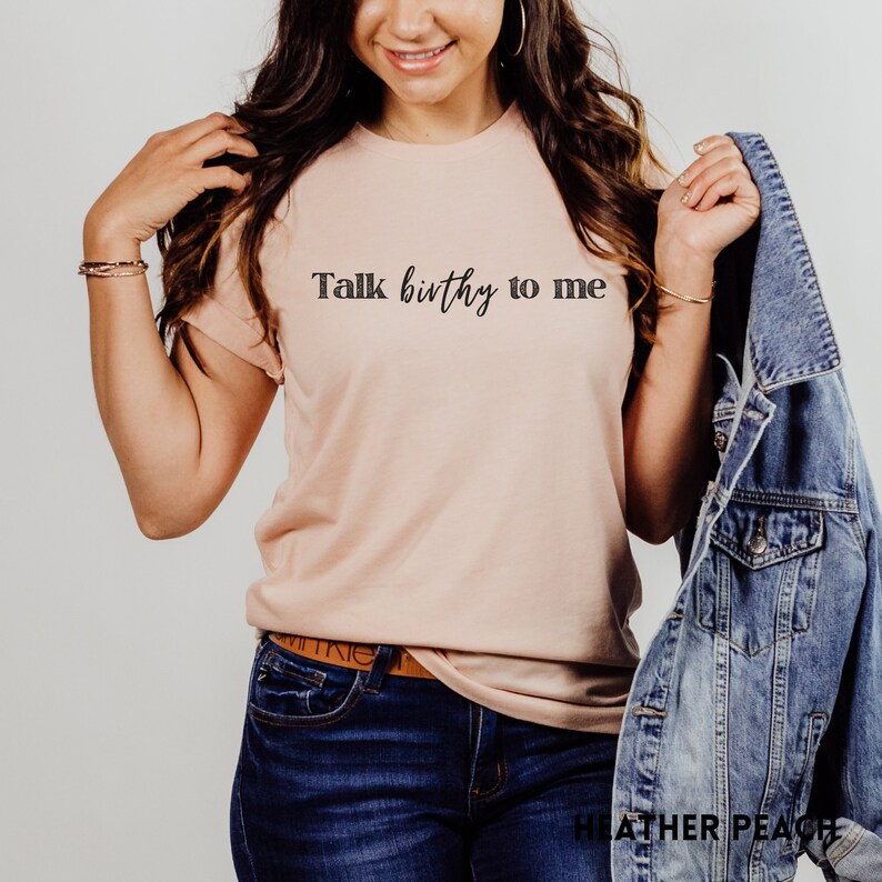 Puede incluir: Una camiseta rosa claro con el texto "Talk birthy to me" en letras negras.