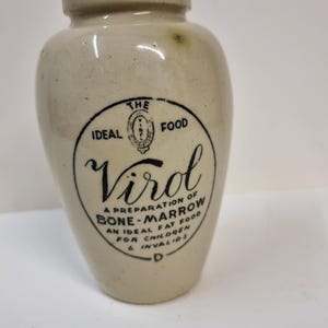 Puede incluir: Un tarro de cerámica blanco con una etiqueta negra que dice "The Ideal Food Virol A Preparation of Bone-Marrow An Ideal Fat Food For Children & Invalids".