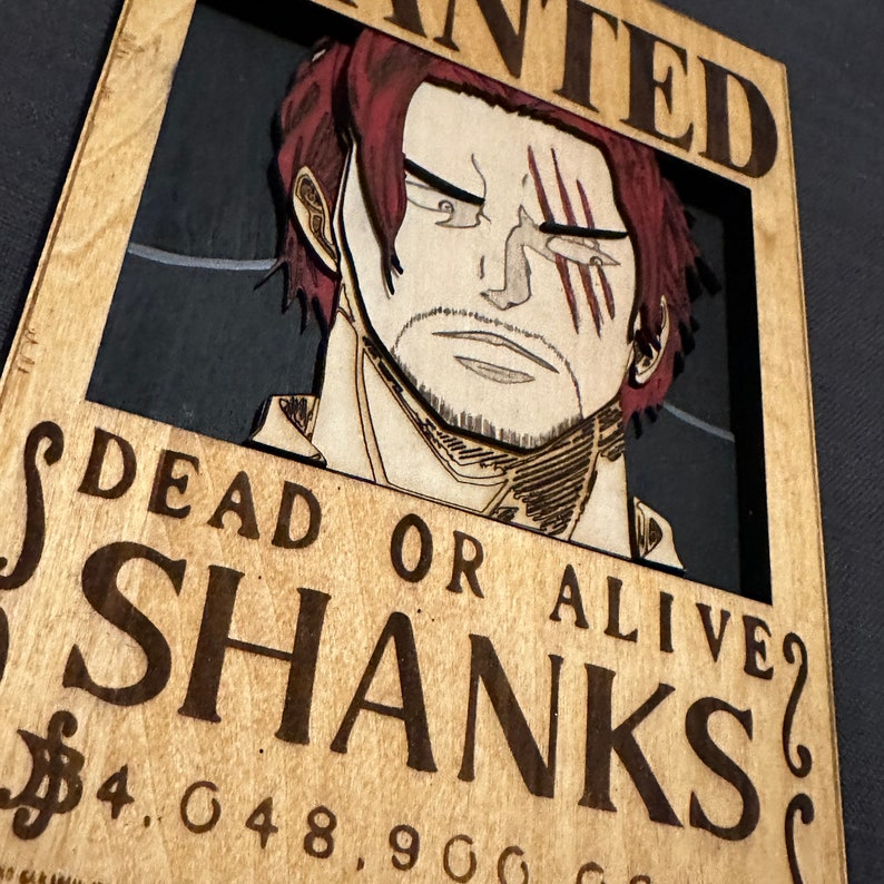 Pode incluir: Um cartaz de procurado de madeira com uma imagem de desenho animado de um homem ruivo com uma cicatriz no olho. O cartaz diz "WANTED DEAD OR ALIVE SHANKS 4.048.900.000 &euro;"