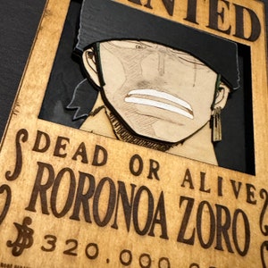Pode incluir: Um cartaz de procurado de madeira com uma imagem de desenho animado de um homem com cabelo preto e uma bandana preta. O cartaz diz "DEAD OR ALIVE" e "RORONOA ZORO" com uma recompensa de $ 320.000.000.