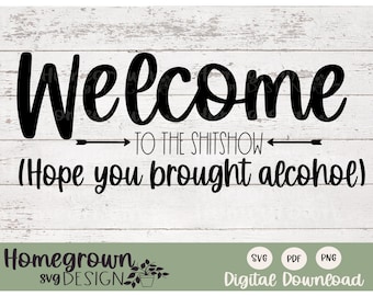 May include: Black and white text on a woodgrain background that reads "Welcome to the shitshow (Hope you brought alcohol)". The text is in a handwritten font. Below the text is a green banner with the words "Homegrown svg DESIGN" in black text. Below the banner are three white circles with the words "SVG", "PDF", and "PNG" in black text. Below the circles is the text "Digital Download" in black text.