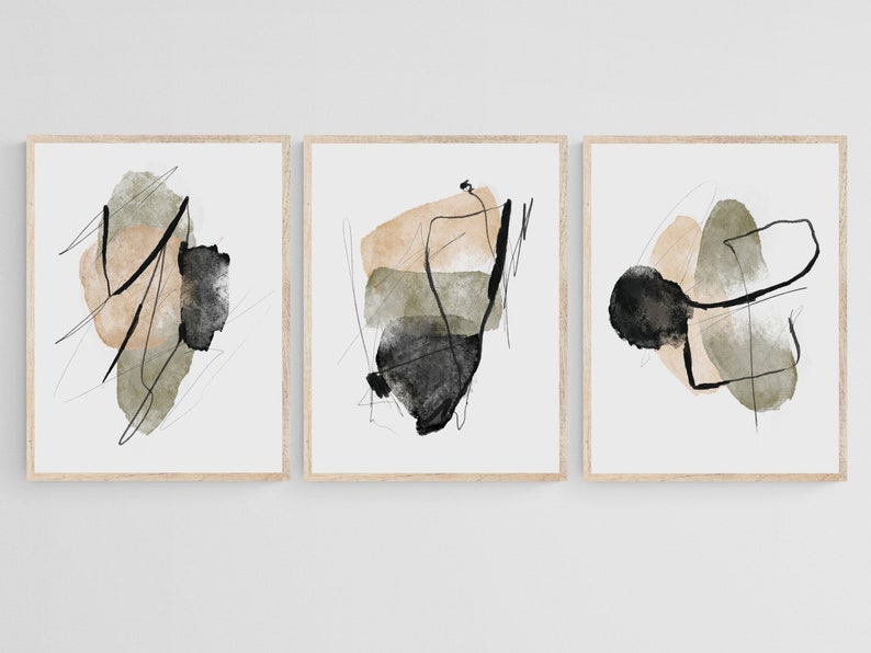 May include: Set of three abstract art prints with black, beige, and green watercolor shapes. The prints are framed in a light wood frame.