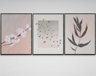 Puede incluir: Tres impresiones enmarcadas con diseños minimalistas. La impresión de la izquierda presenta una rama de flores blancas sobre un fondo rosa y gris. La impresión del centro muestra una bandada de pájaros negros volando sobre un fondo degradado gris y rosa. La impresión de la derecha presenta una sola hoja negra sobre un fondo rosa y gris.