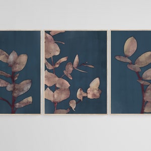 May include: A set of three framed prints featuring abstract botanical illustrations in shades of brown and beige on a deep blue background.