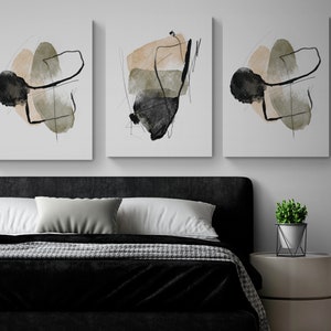 May include: Three abstract art prints with black, brown, and green shapes on a white background. The prints are hanging on a white wall above a black headboard and a bed with a black and white patterned blanket.
