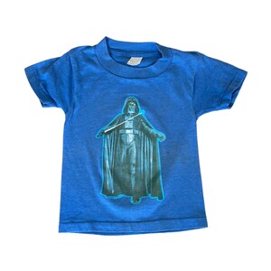 May include: A blue short-sleeved t-shirt with a graphic of Darth Vader from Star Wars.