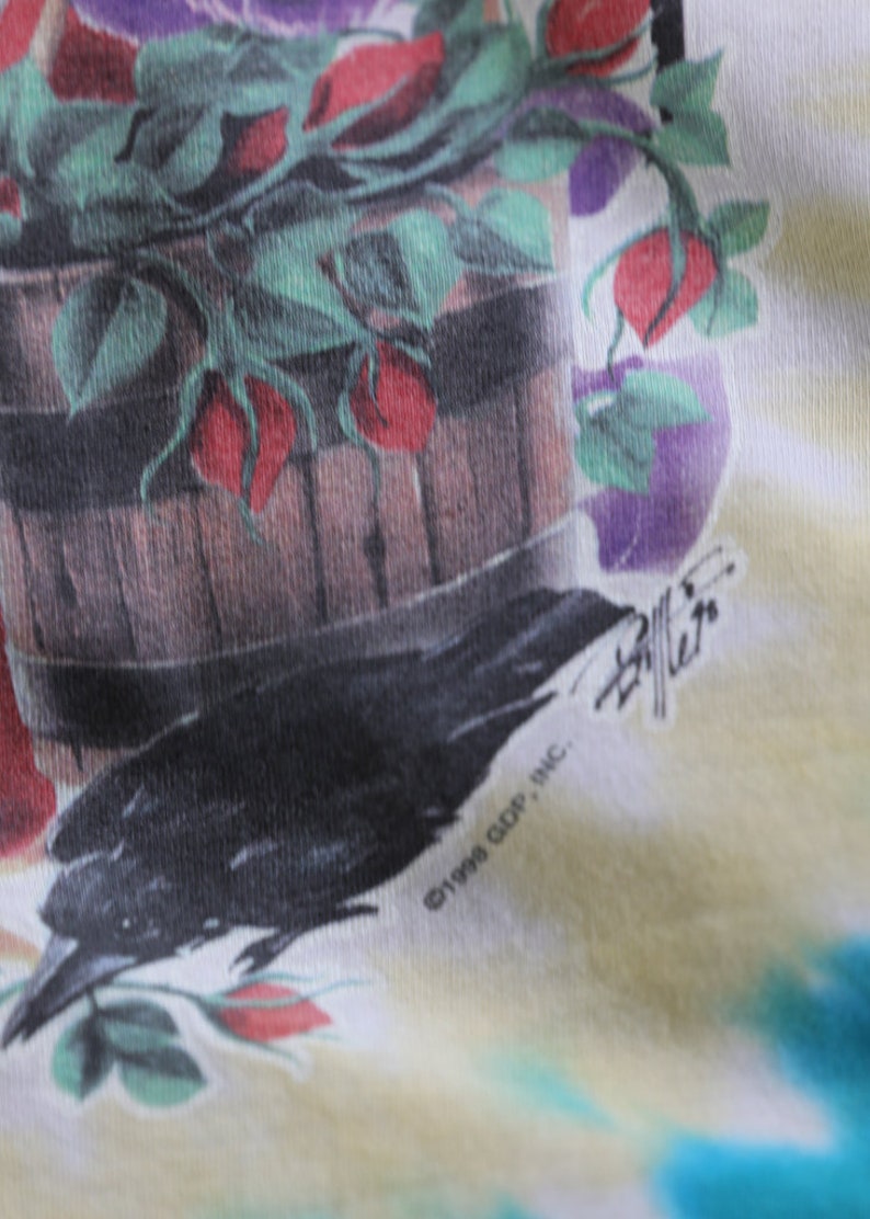 May include: A tie-dye t-shirt with a black crow and a wooden bucket filled with red roses and green leaves. The shirt has the text "&copy;1998 GDP, INC." and a signature.