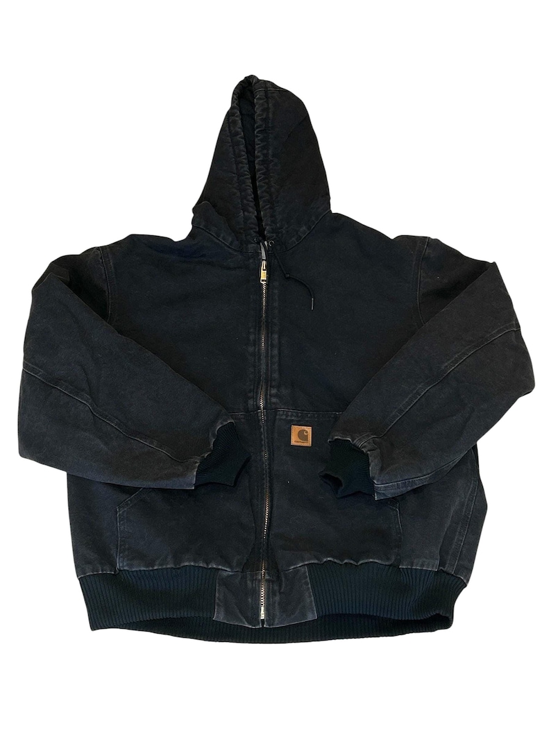 May include: Black hooded zip-up jacket with a brown logo patch. The jacket features a drawstring hood, ribbed cuffs, and a ribbed hem. The jacket has a full-length zipper and two front pockets.