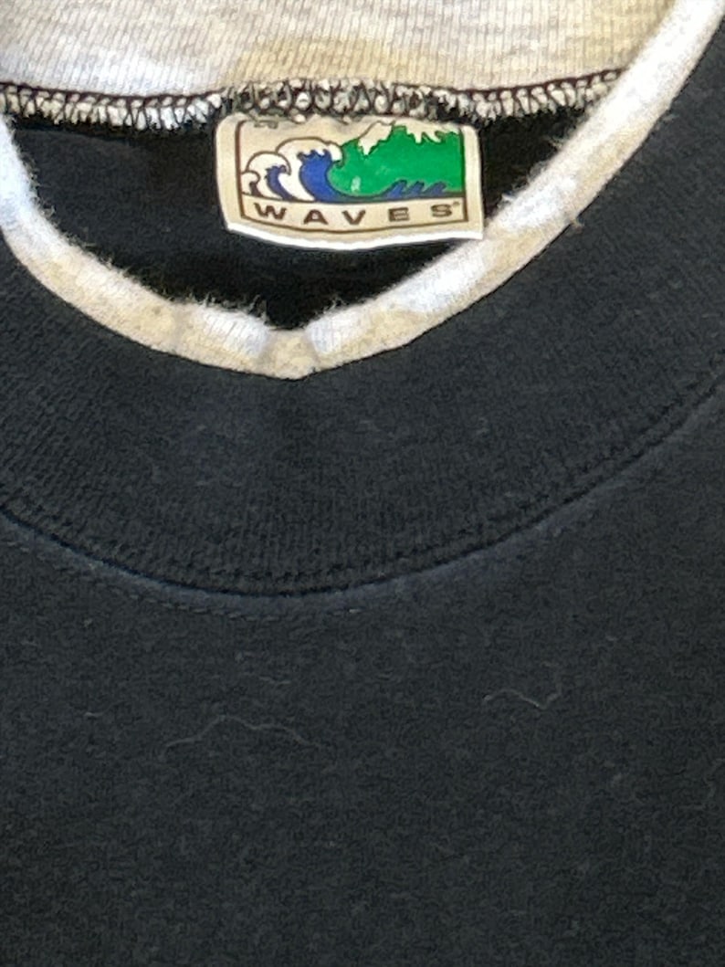 May include: Black sweatshirt with a white ribbed collar and a green and white label that says "WAVES" in all caps.