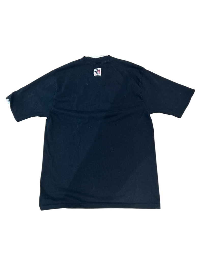 May include: Black short-sleeved t-shirt with a small American flag patch on the back.