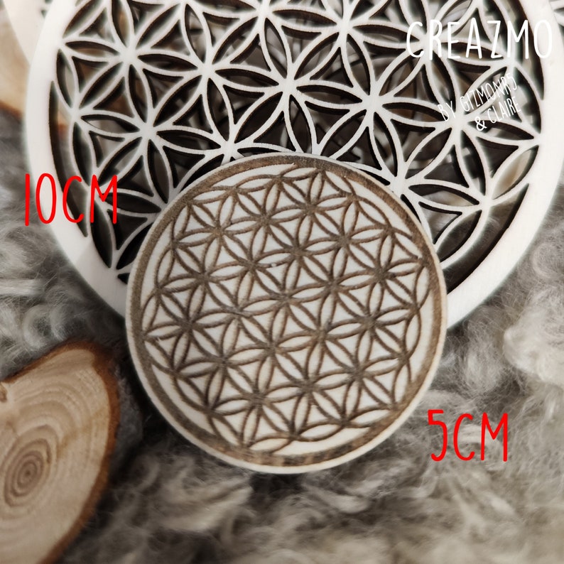 K&ouml;nnte beinhalten: Zwei dekorative Holzst&uuml;cke mit einem geometrischen Blumen des Lebens-Design. Eines ist ein 10 cm Kreis, das andere ein 5 cm Kreis. Das gr&ouml;&szlig;ere St&uuml;ck ist wei&szlig;, das kleinere hellbraun.