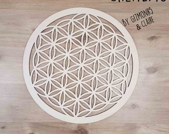 Könnte beinhalten: Runde, cremefarbene Wandkunst aus Holz mit einem lasergeschnittenen Flower-of-Life-Design. Das Kunstwerk befindet sich vor einem hellbraunen Holzmaserungshintergrund. Der Text "CREAZMO BY GIZMONR5 & CLAIRE" befindet sich in der oberen rechten Ecke.