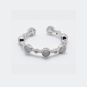 May include: A silver adjustable ring with five white stones set in a silver bezel. Each stone is surrounded by smaller silver accents.
