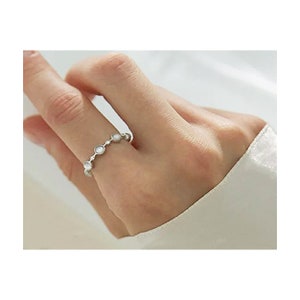 May include: A silver ring with a row of small, round, white stones.