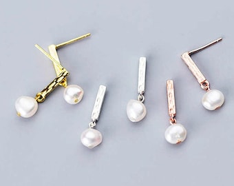 May include: Four pairs of earrings with a pearl and a small bar pendant. The bars are in gold, silver, and rose gold.