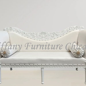 May include: White carved wooden chaise lounge with white upholstery and two decorative pillows. The chaise lounge has a curved back and ornate details.  Tiffany Furniture Chicago.