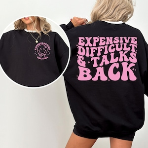 May include: Black sweatshirt with a pink graphic on the back that says "Expensive Difficult & Talks Back" in a retro font. The graphic also includes stars and glitter.