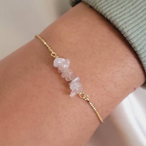 Könnte beinhalten: Ein zartes Armband aus einer goldenen Kette mit einem Cluster aus kleinen, hellrosa Rosenquarzsteinen.