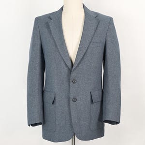 Op de afbeelding: Een blauwe blazer met een sluiting met twee knopen, een revers met inkeping en twee voorzakken. De jas wordt op een mannequin gepresenteerd tegen een witte achtergrond. De blazer heeft een klassieke, getailleerde pasvorm.