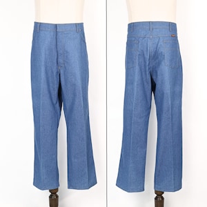 May include: Blue denim trousers with a classic, straight-leg cut. The trousers have a traditional five-pocket design, belt loops, and a button and zip fastening. The denim is a medium wash, and the trousers are displayed on a mannequin.