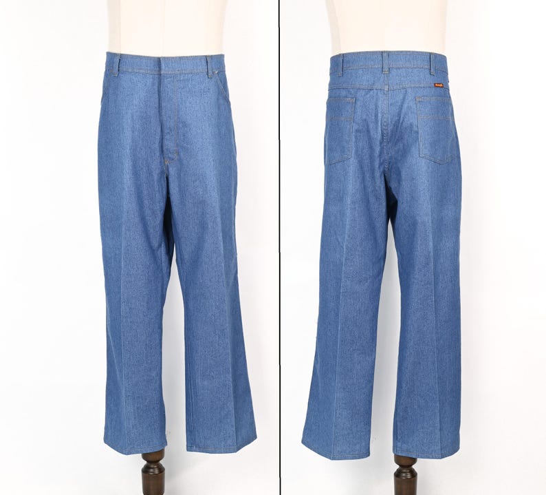 May include: Blue denim trousers with a classic, straight-leg cut. The trousers have a traditional five-pocket design, belt loops, and a button and zip fastening. The denim is a medium wash, and the trousers are displayed on a mannequin.