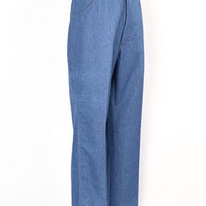 May include: Light blue denim jeans with a straight leg cut. The jeans have a classic five-pocket design and a button and zip closure. The jeans are displayed on a mannequin.
