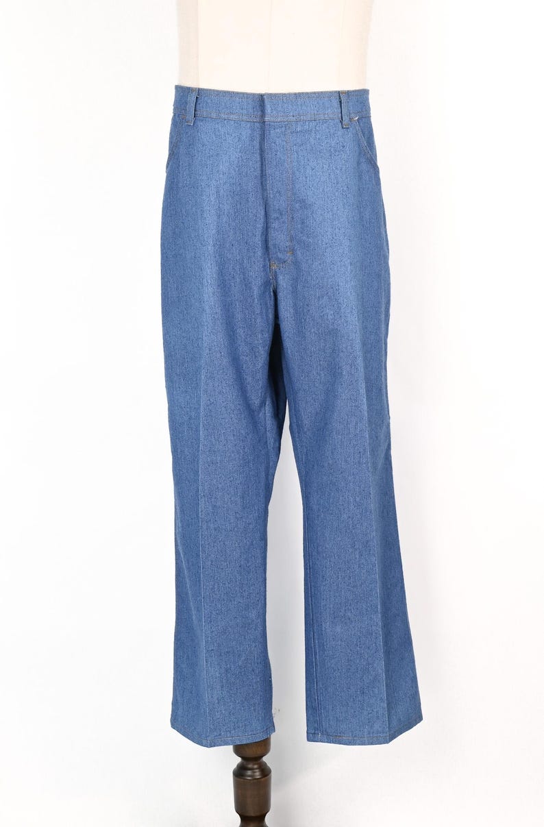 May include: Light blue denim trousers with a flared leg. The trousers feature a classic five-pocket design and a button and zip closure. The denim fabric has a medium wash and a slight sheen. The trousers are displayed on a mannequin.