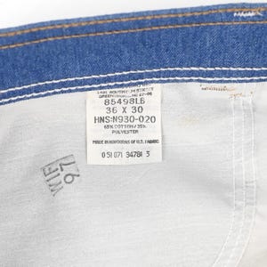 K&ouml;nnte beinhalten: Nahaufnahme der Innenseite einer blauen Jeans. Ein wei&szlig;es Etikett ist in den Stoff eingen&auml;ht und zeigt die Gr&ouml;&szlig;e 36 x 30 sowie weitere Details. Die Jeans besteht aus 65 % Baumwolle und 35 % Polyester.