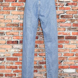 Peut inclure: Un jean en denim bleu clair &agrave; taille haute et &agrave; jambe droite. Le jean a une braguette &agrave; boutons et des passants de ceinture.