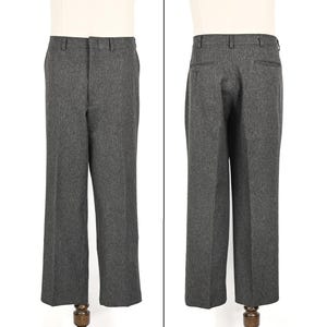 May include: A pair of gray wool trousers displayed on a mannequin. The pants have a straight leg design, a button and zipper closure, and belt loops. The back view shows two pockets. The fabric has a subtle textured appearance.