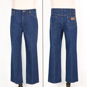 May include: A pair of blue denim jeans, displayed front and back. The jeans have a classic five-pocket design, a button and zipper closure, and a flared leg. The back features two pockets and a brown leather patch.