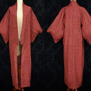 May include: A red and blue striped kimono with long sleeves and a wide collar. The kimono is made of a lightweight fabric and has a relaxed fit.