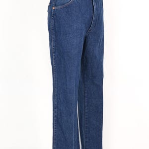 May include: Dark blue denim jeans with a classic straight leg fit. The jeans have a button and zipper closure, front and back pockets, and belt loops. The jeans are displayed on a mannequin.